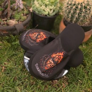 Pantuflas Traumas.mx – Edición "Skull on Fire" Dales a tus pies el alivio que necesitan después de la batalla. Estas pantuflas combinan la calidez de un calzado de descanso con el diseño agresivo de Traumas.mx, presentando la icónica máscara envuelta en llamas sobre un fondo negro sólido.