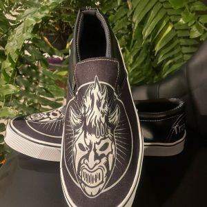 Tenis Slip-On Traumas.mx – Edición "Iconic Black" Lleva el estilo de los encordados a la calle con los Tenis Slip-On de Traumas.mx. Este modelo ofrece una silueta moderna y estilizada, perfecta para quienes prefieren un look más sobrio pero con toda la esencia del pancracio mexicano. Su construcción híbrida combina tela transpirable en el empeine con refuerzos sintéticos, garantizando un calzado resistente y ligero.